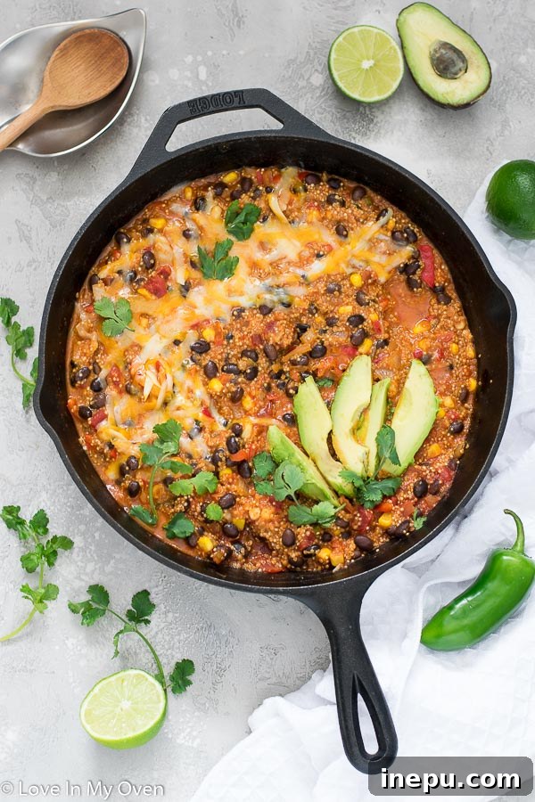 A vibrant, cheesy Mexican quinoa casserole in a skillet, garnished with fresh cilantro and avocado slices. Perfect vegetarian one-pan meal.