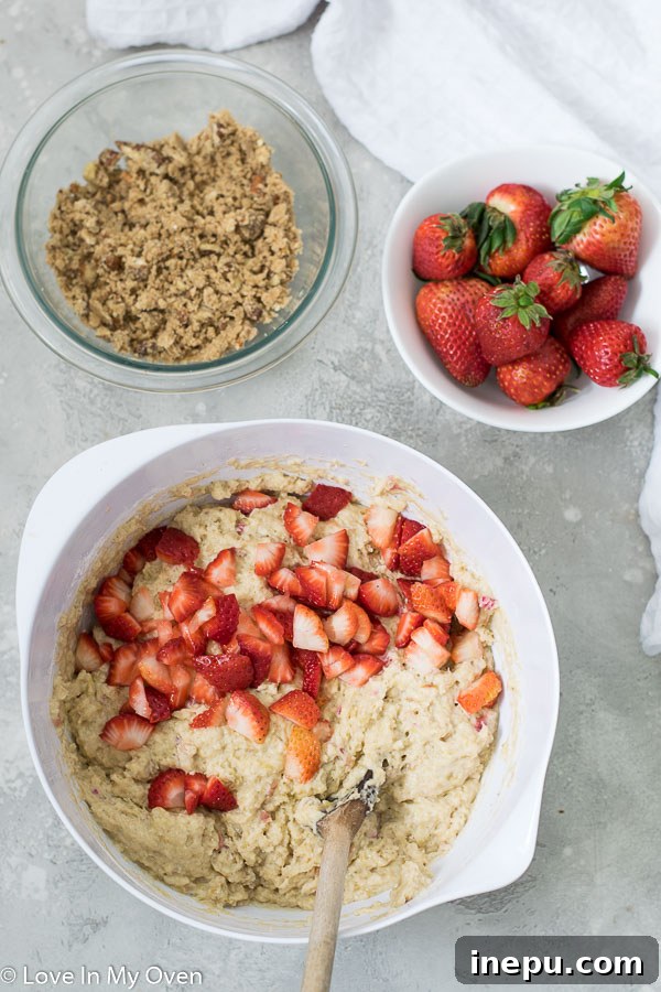 Close-up of muffin batter being prepared with fresh rhubarb and strawberries.