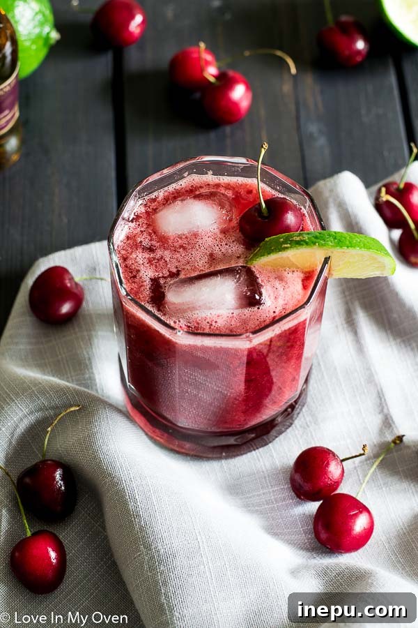 Crimson Cherry Delight 3 Close-up of a Cherry Lime Whiskey Sour, showcasing its vibrant red color and fresh garnish