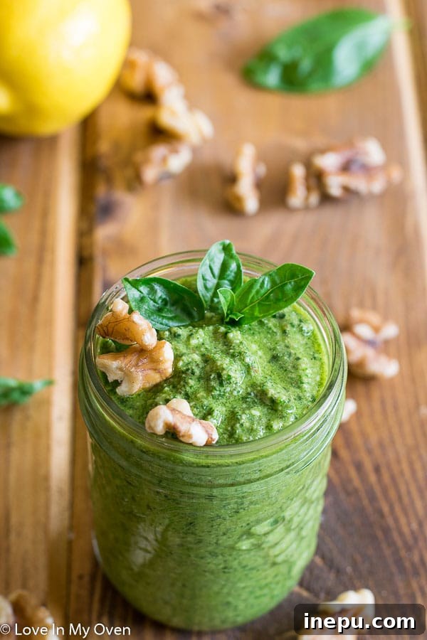 Freshly made walnut basil pesto in a beautiful ceramic bowl, with basil leaves and walnuts scattered artfully around, hinting at its natural ingredients.