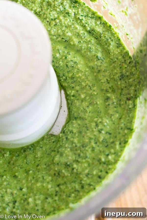 Dynamic shot of walnut basil pesto being actively blended in a food processor, highlighting the creation process.