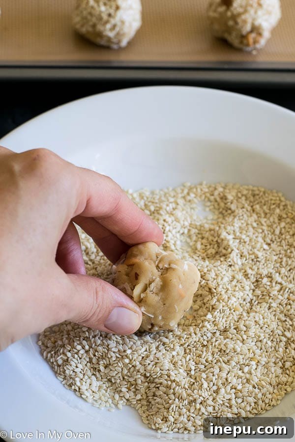 Cookie dough balls coated with sesame seeds, ready for baking.
