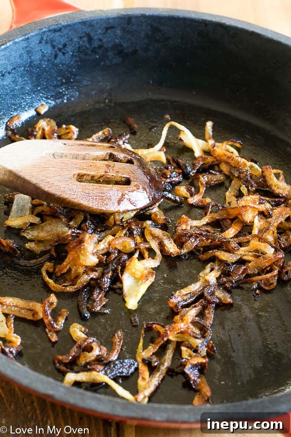 Sweet & Savory Chorizo Onion Pizza 4 A close-up of thinly sliced yellow onions caramelizing in a cast iron skillet.