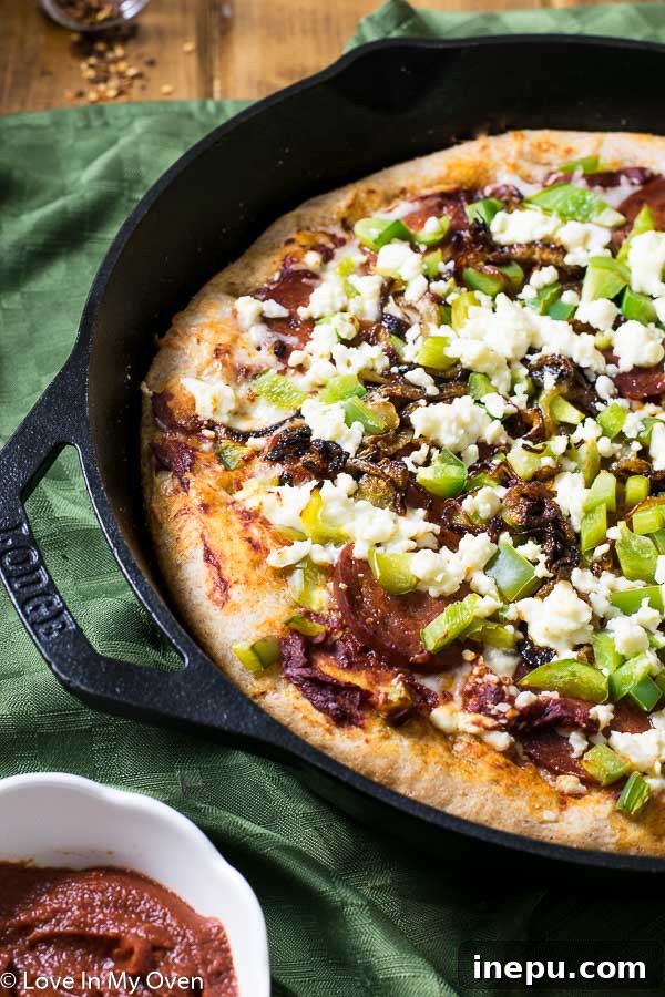 Sweet & Savory Chorizo Onion Pizza 6 A slice of Chorizo and Caramelized Onion Skillet Pizza being lifted from the pan, showing the thick crust and abundant toppings.