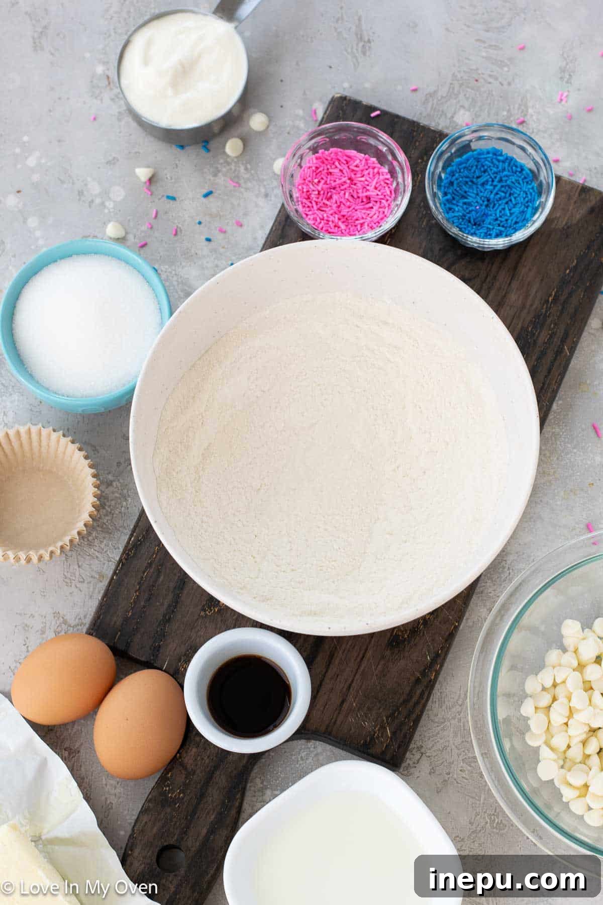 Sweet Gender Surprise 4 Ingredients for making homemade white chocolate gender reveal cupcakes laid out on a kitchen counter.